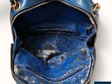 the inside of a blue purse with a gold chain hanging from it