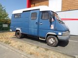 une petite camionnette bleue garée devant un immeuble