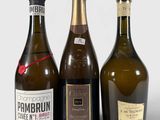 trois bouteilles de vin posées les unes à côté des autres sur une surface blanche