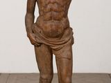 statue of a man standing on a wooden base with his hands in his pockets