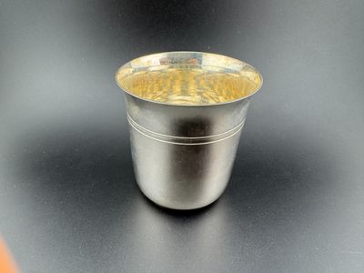 a silver cup with a wooden lid sitting on a table