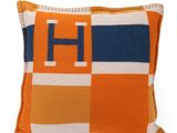un gros plan sur un coussin orange et bleu sur lequel figure la lettre h