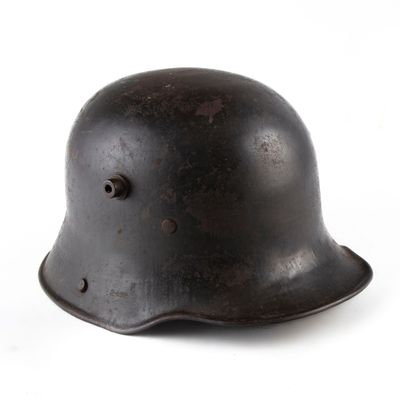 un vieux casque noir posé sur une surface blanche, avec un fond blanc