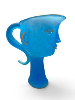 un vase en verre bleu sur lequel est représenté un visage