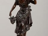 bronze statue of a woman holding a basket of flowers on a table