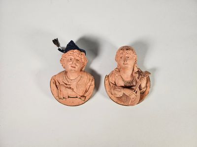 deux figurines représentant un homme et une femme sont assises sur une surface blanche