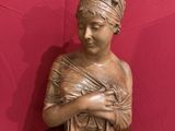 bronze statue of a woman holding a basket on a wooden table
