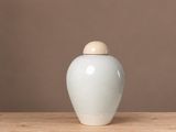 un vase blanc posé sur une table en bois, sur fond marron