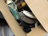 une boîte en carton posée par terre, contenant des chaussures