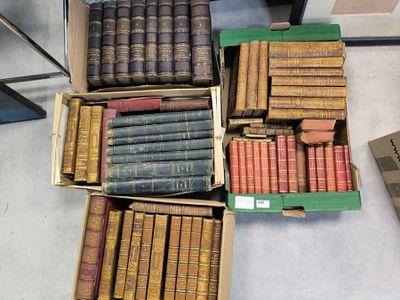 Des cartons remplis de vieux livres sont empilés par terre dans une pièce