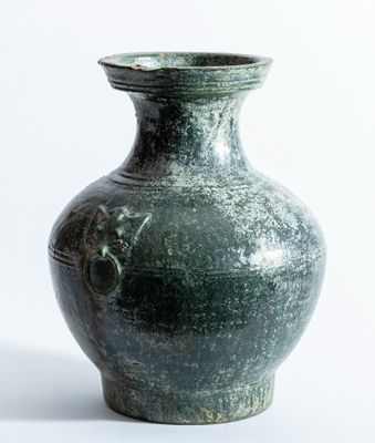un vase vert posé sur une surface blanche