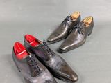 pair of men ' s shoes with red soles on a grey surface