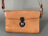 an image of a tan purse with a lock on it