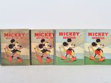 three mickey mouse books are lined up on a white surface