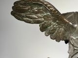 a bronze statue of a bird with wings on it ' s head