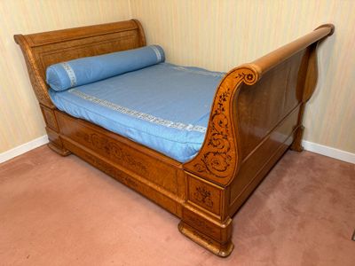 un lit recouvert d'un drap bleu, dans un coin de la pièce