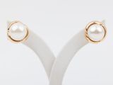 a pair of gold and pearl earrings on a white stand