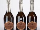 trois bouteilles de champagne posées les unes à côté des autres sur une surface blanche