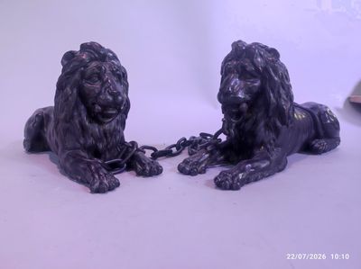 two statues of lions chained to chains on a white surface