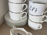 Plusieurs tasses et soucoupes sont empilées sur une étagère dans une cuisine