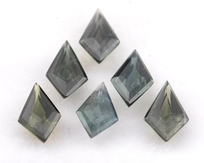 quatre morceaux de verre gris et vert sur une surface blanche