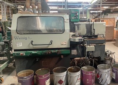 several buckets of paint are lined up next to a machine in a factory