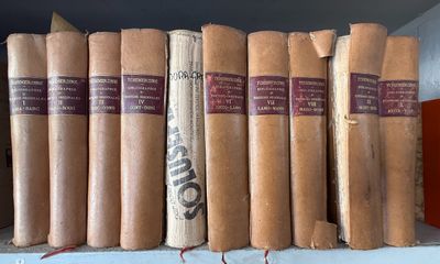plusieurs vieux livres sont alignés sur une étagère dans une bibliothèque