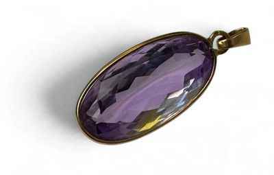 un gros plan d'un pendentif en verre violet sur fond blanc