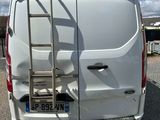 a white van parked in a parking lot with a ladder on the back of the van