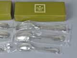 six silver spoons in a green box on a table