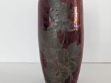 un vase violet orné d'une fleur, posé sur un fond blanc