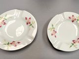 two white plates with pink flowers on them sitting on a table