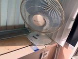 un ventilateur posé sur un bureau près d'une fenêtre