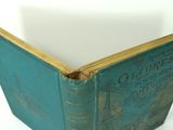an old green book sitting on top of a table next to a white wall