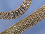 deux bracelets à chaîne en or et un bracelet à chaîne en or sur fond bleu