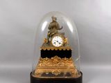 une horloge en or sous un dôme de verre sur une table