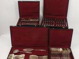 four pieces of silverware in a red case on a white surface