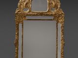 un miroir richement sculpté, avec un cadre doré sur fond gris
