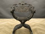 an antique iron chair on a wooden floor with a gray background