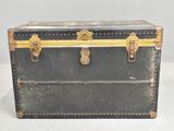 a black trunk with gold trim and brass hardware on it