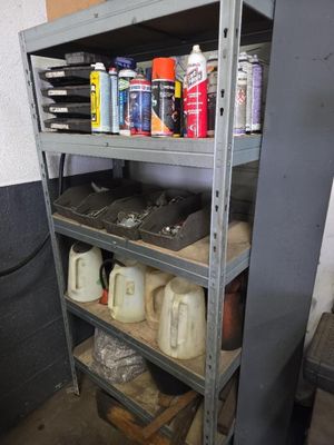 une étagère métallique sur laquelle sont posés des bidons et encore des bidons de peinture