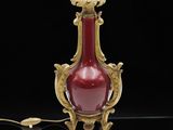 un vase rouge et doré posé sur une surface noire