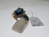 a close up of a ring with a blue stone surrounded by diamonds