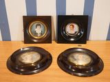 two black plates with pictures of women on them sitting on a wooden table