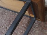 un banc en bois avec une structure métallique posé à même le sol
