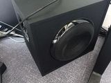 a black speaker sitting on top of a desk next to a chair