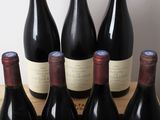 six bottles of wine sit in a wooden crate on a table