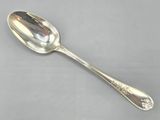 une cuillère ancienne en argent posée sur une surface grise, avec un manche en argent