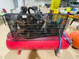 a dog in a cage sitting on top of a red air compressor