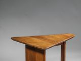 une table en bois dont le plateau est de forme triangulaire, sur fond gris